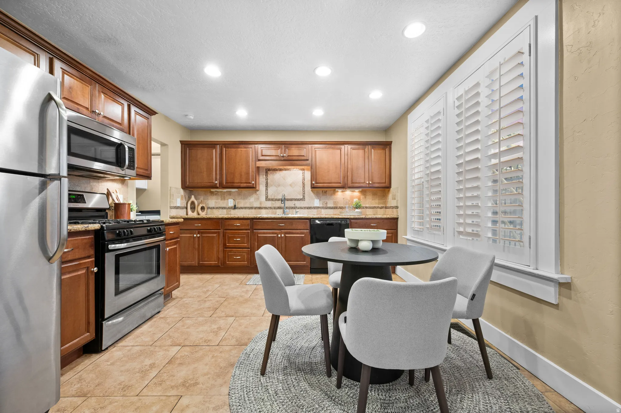 Kitchen with stainless steel appliances, recessed lighting, light stone countertops, light tile patterned floors, and wood finish cabinets