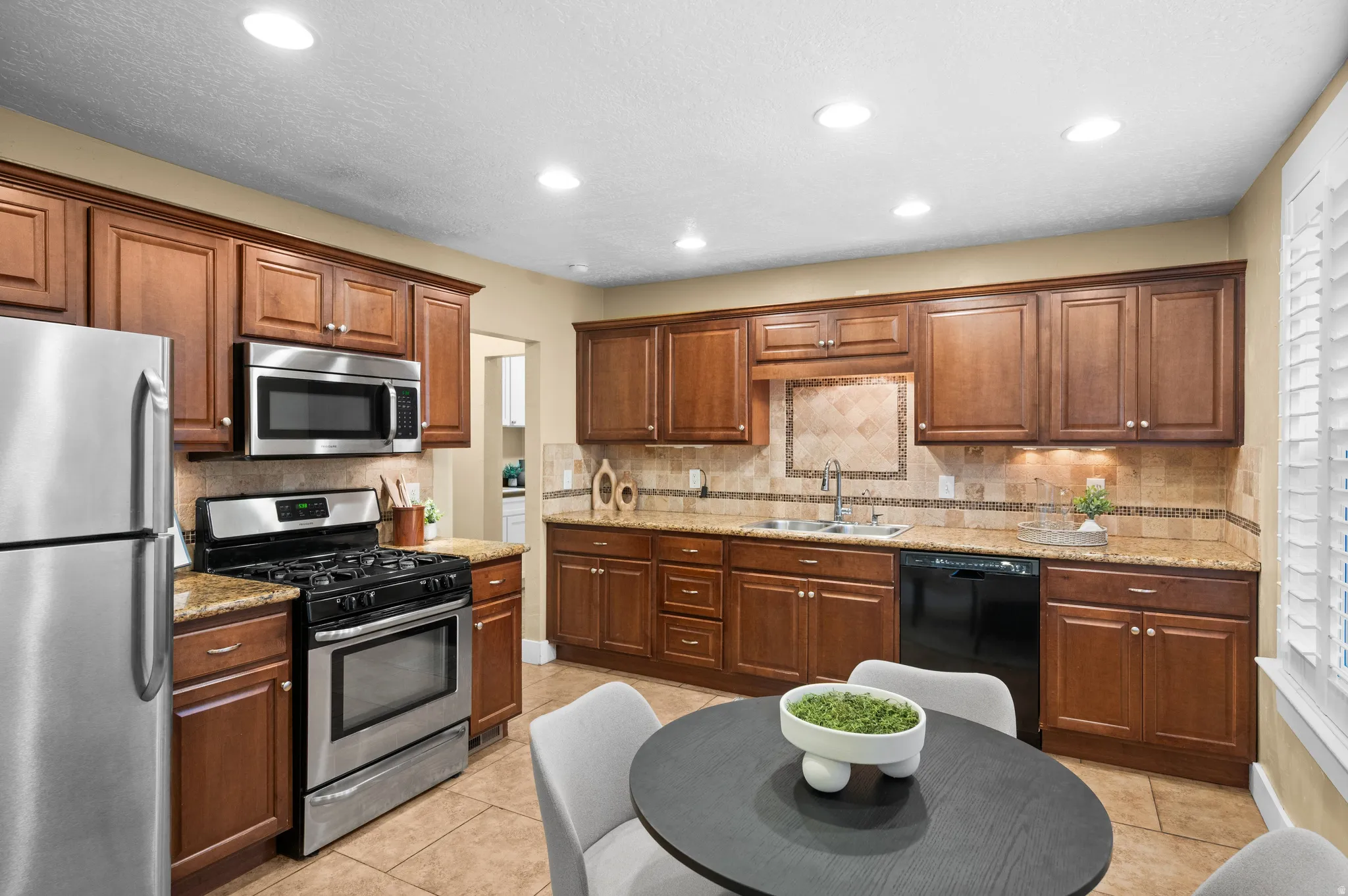 Kitchen with stainless steel appliances, light stone countertops, recessed lighting, wood finish cabinets, and light tile patterned flooring