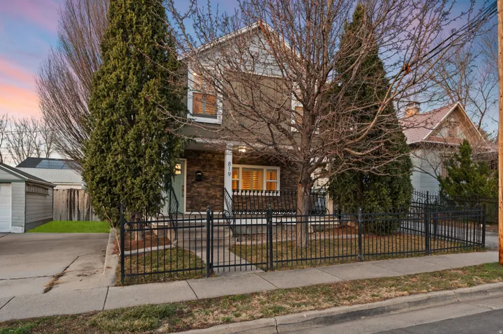 View of property hidden behind natural elements with a porch and a fenced front yard
