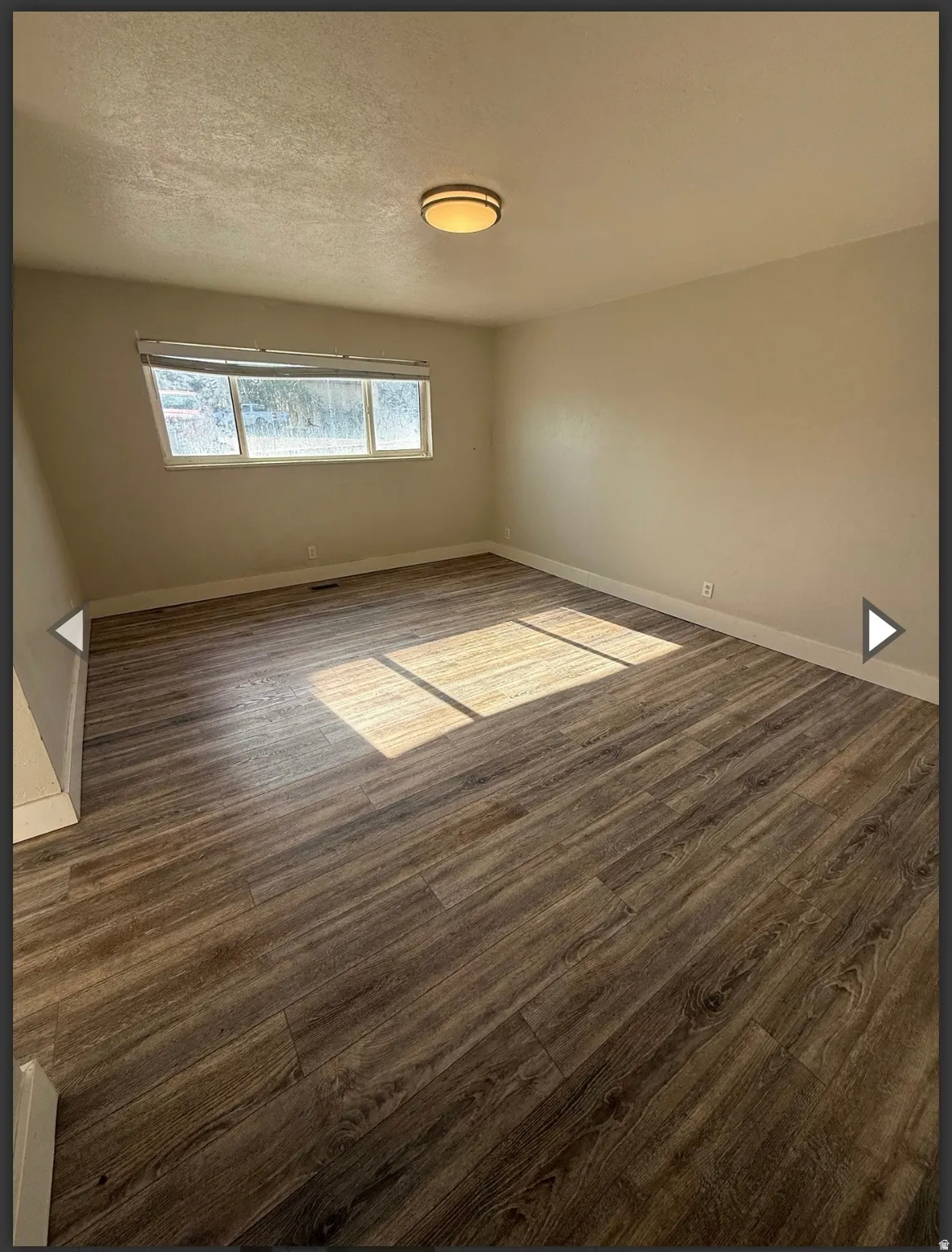 Unfurnished room with dark wood-style floors and a textured ceiling
