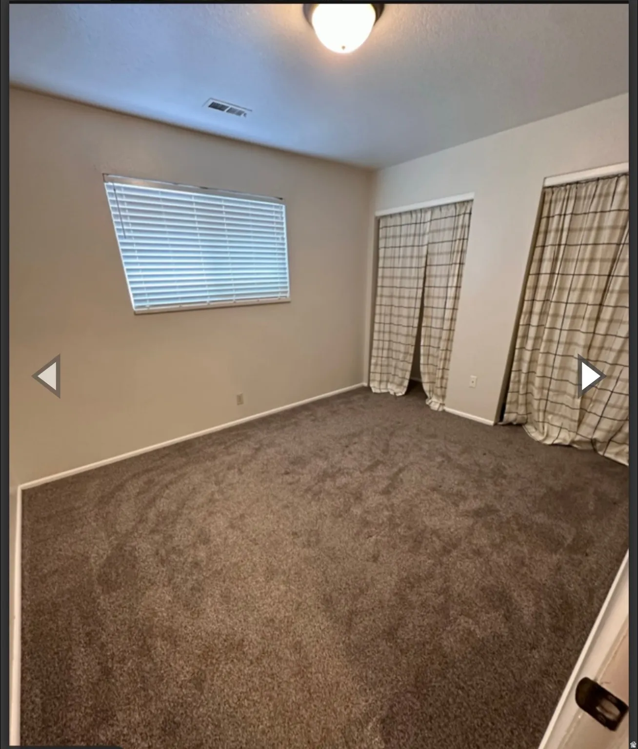 Empty room featuring dark carpet and baseboards