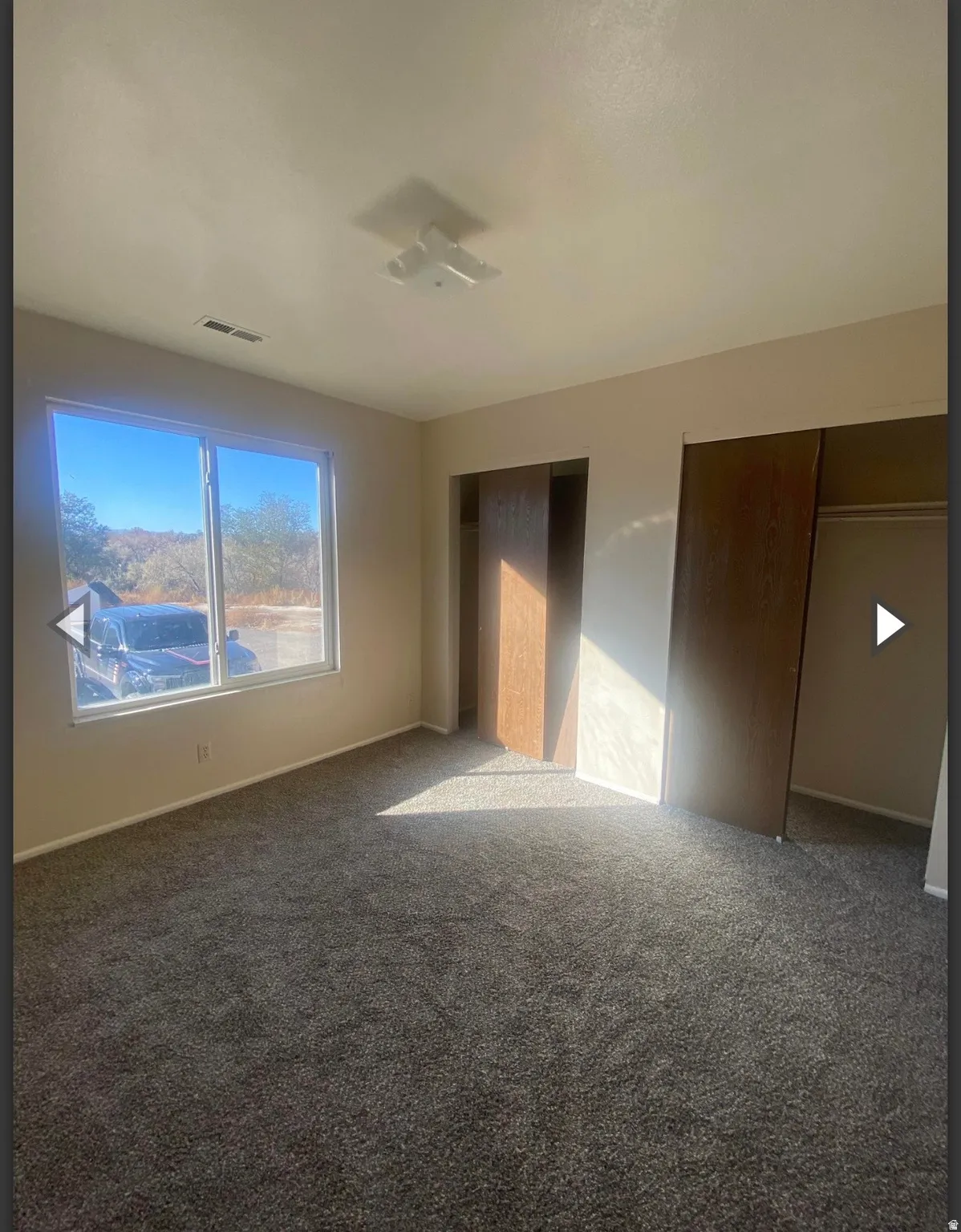 Unfurnished bedroom featuring carpet flooring and two closets