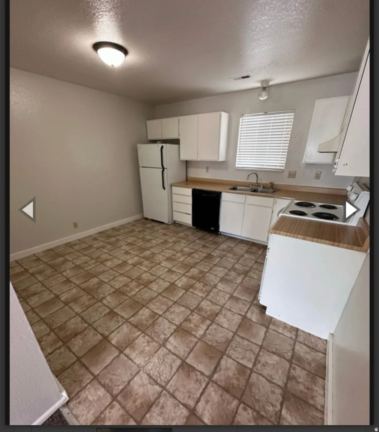 Kitchen featuring white appliances, white cabinets, light countertops, a textured ceiling, and light stone finish flooring