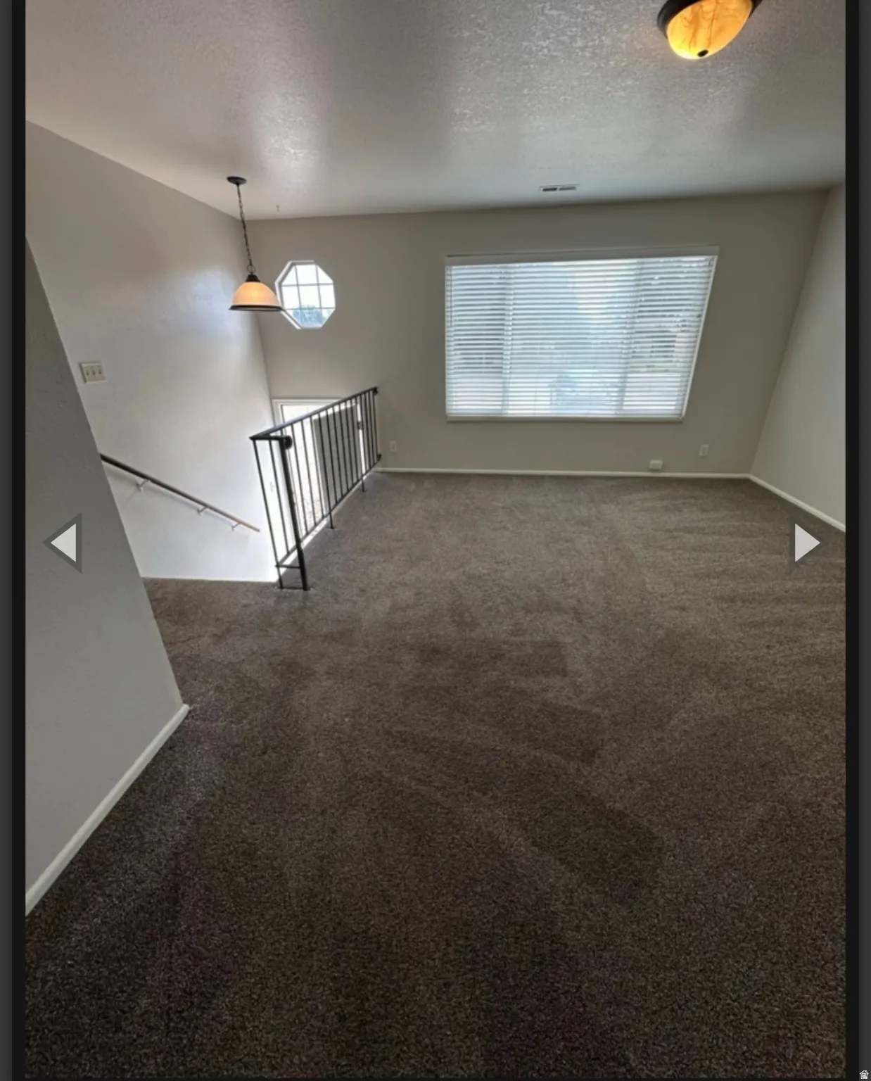 Unfurnished room with dark carpet, a textured ceiling, and healthy amount of natural light