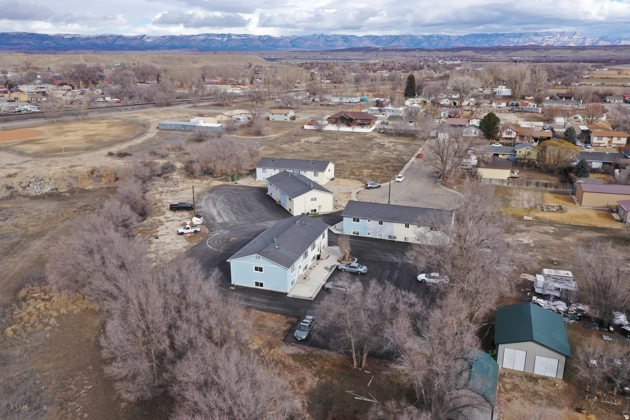 Aerial view of property and surrounding area featuring nearby suburban area and a mountainous background