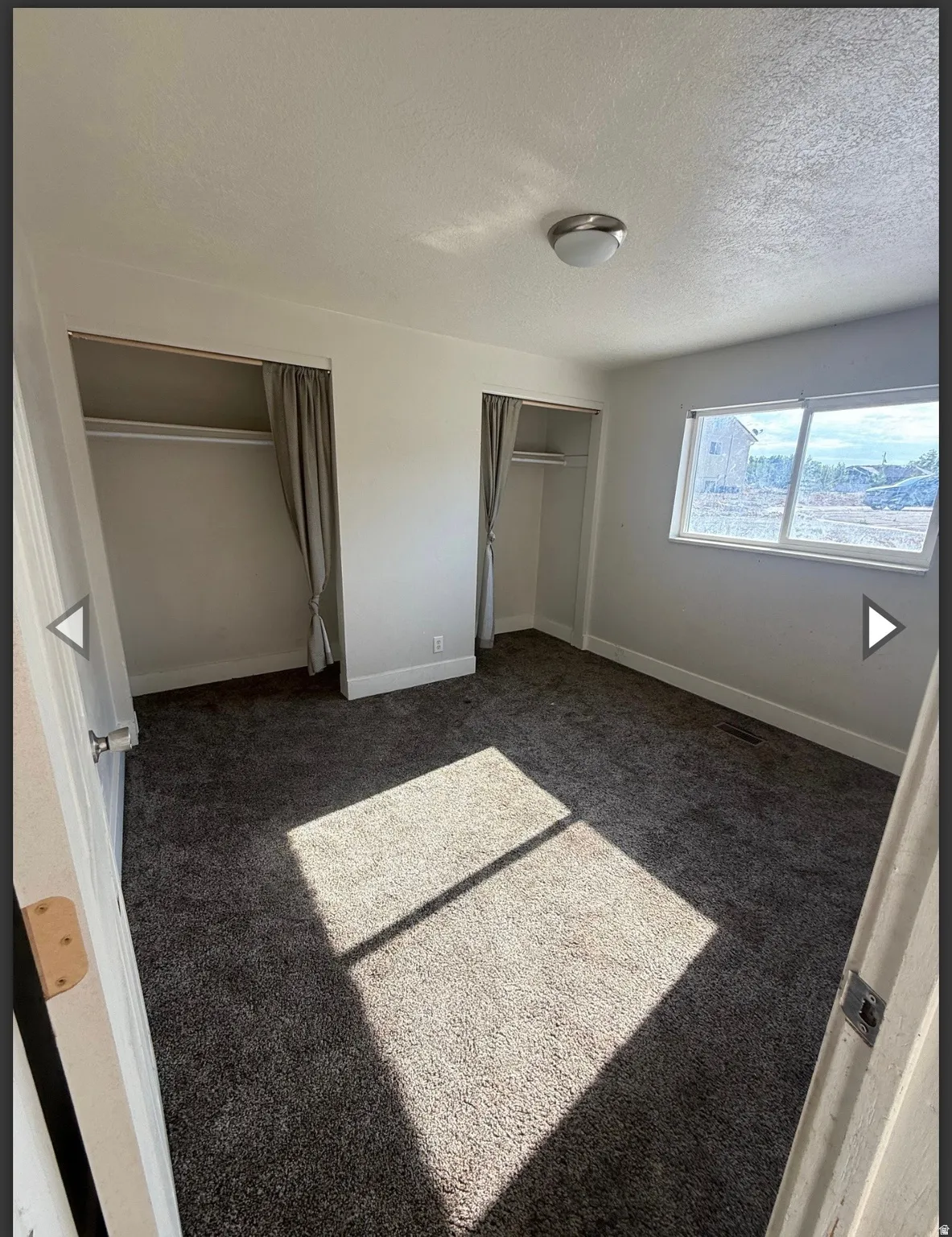 Unfurnished bedroom with multiple closets, carpet floors, and a textured ceiling