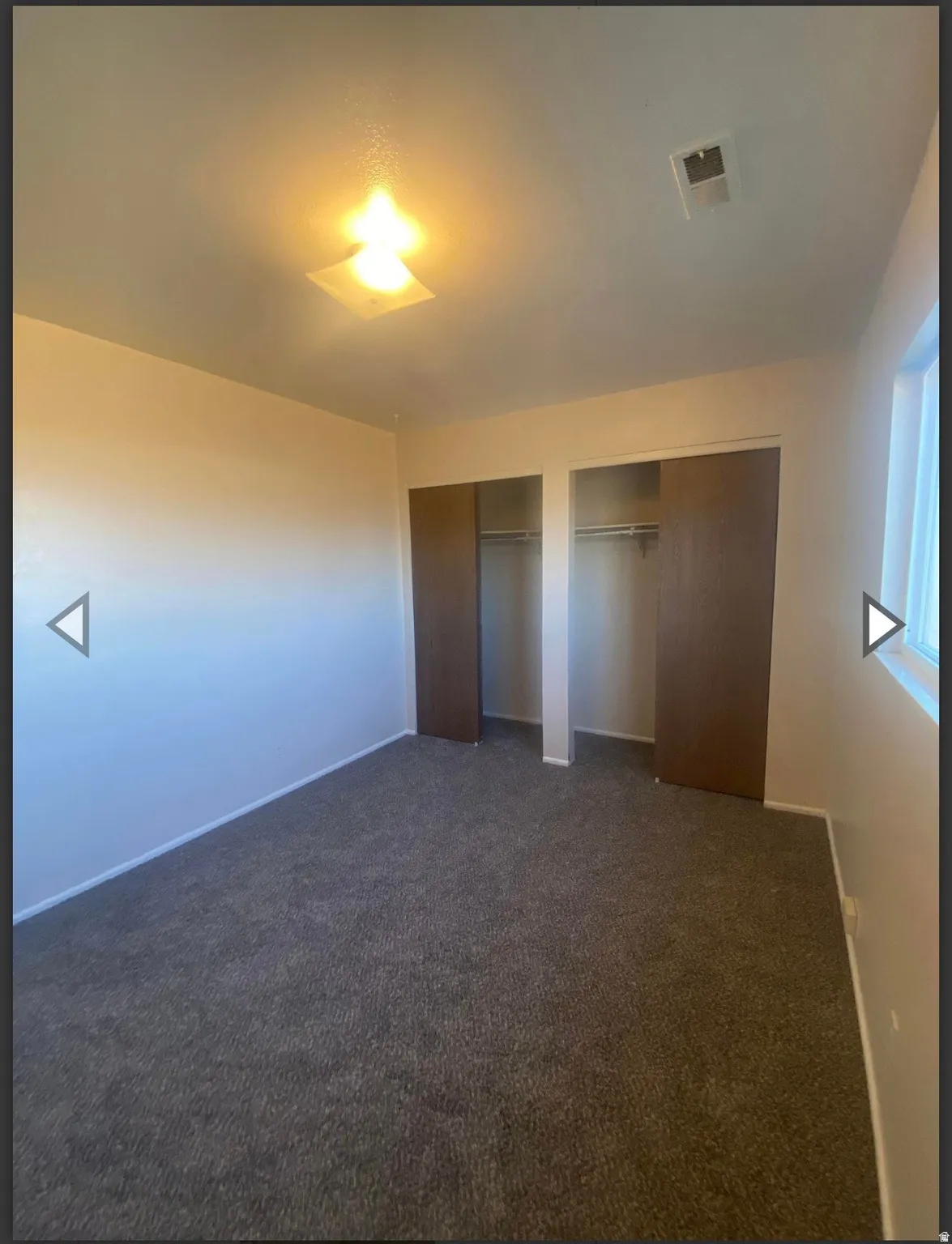 Unfurnished bedroom featuring two closets and dark colored carpet