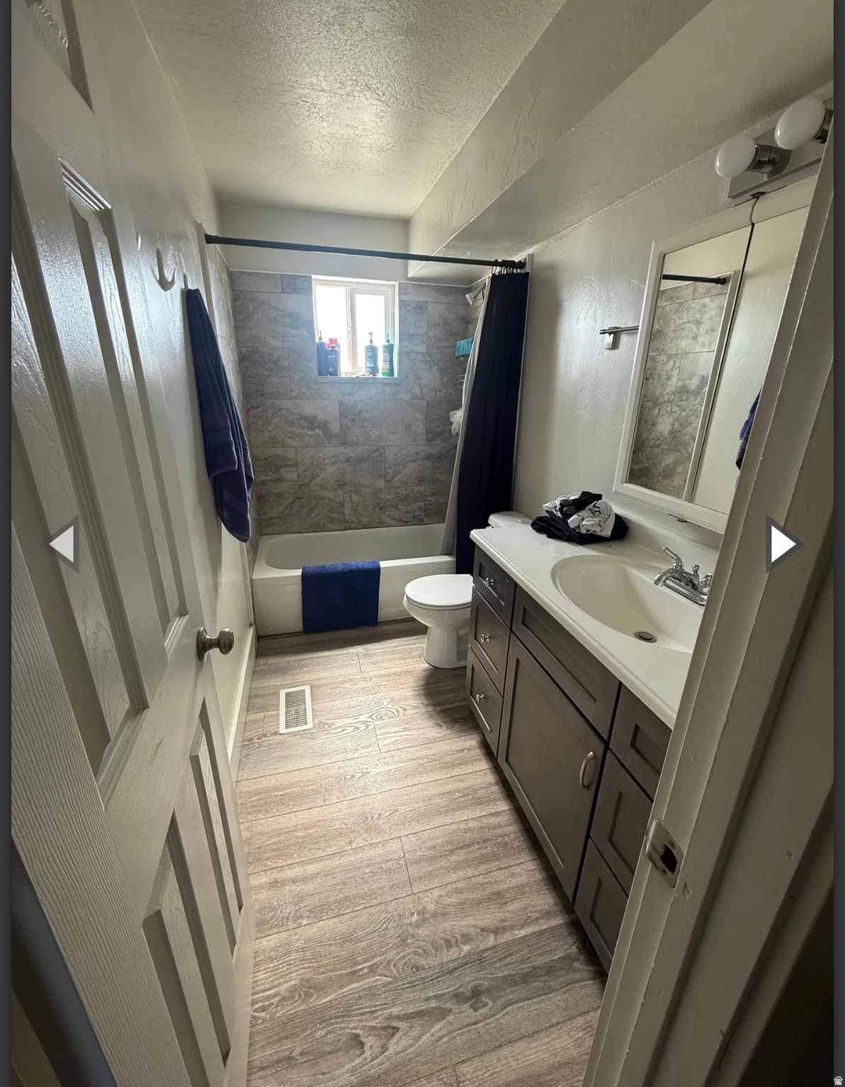Full bathroom featuring vanity, a textured ceiling, shower / bathtub combination with curtain, and light wood-style floors