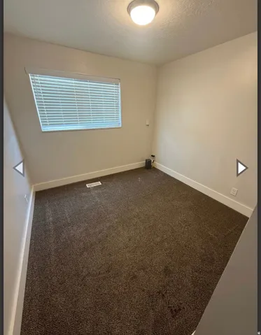 Unfurnished room featuring dark carpet and a textured ceiling
