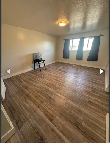 Unfurnished room with dark wood finished floors and a textured ceiling