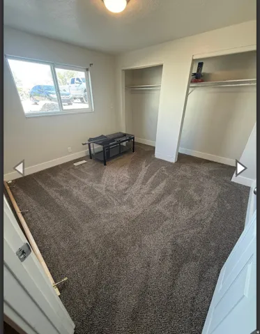 Unfurnished bedroom featuring multiple closets, dark carpet, and a textured ceiling