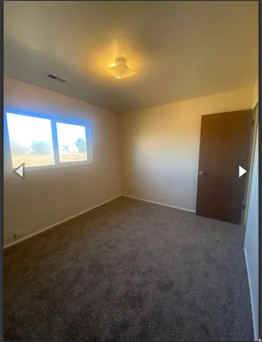 Carpeted empty room featuring baseboards