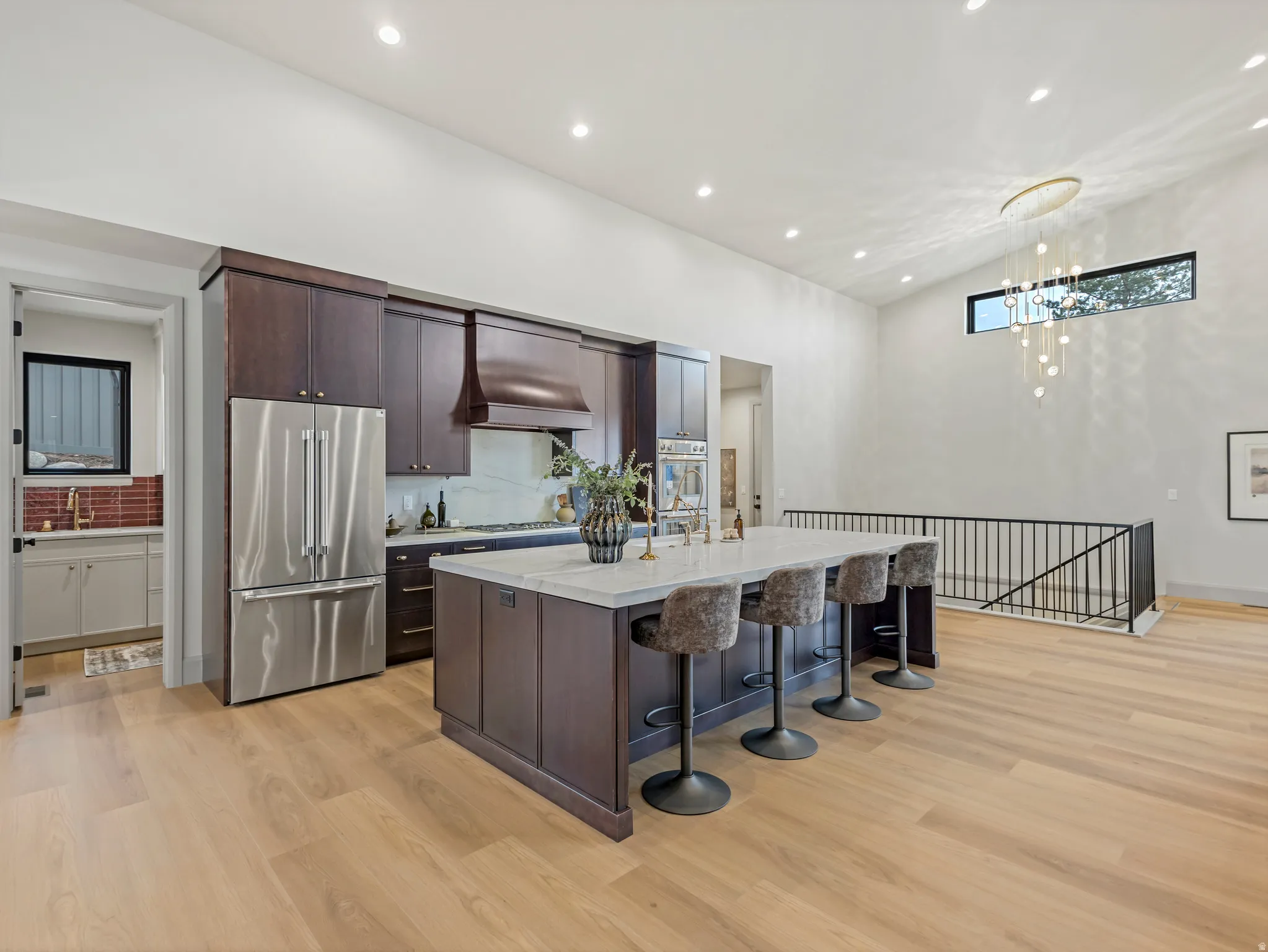 Kitchen with dark wood finish cabinetry, an island with sink, a kitchen breakfast bar, stainless steel appliances, and light wood-style floors