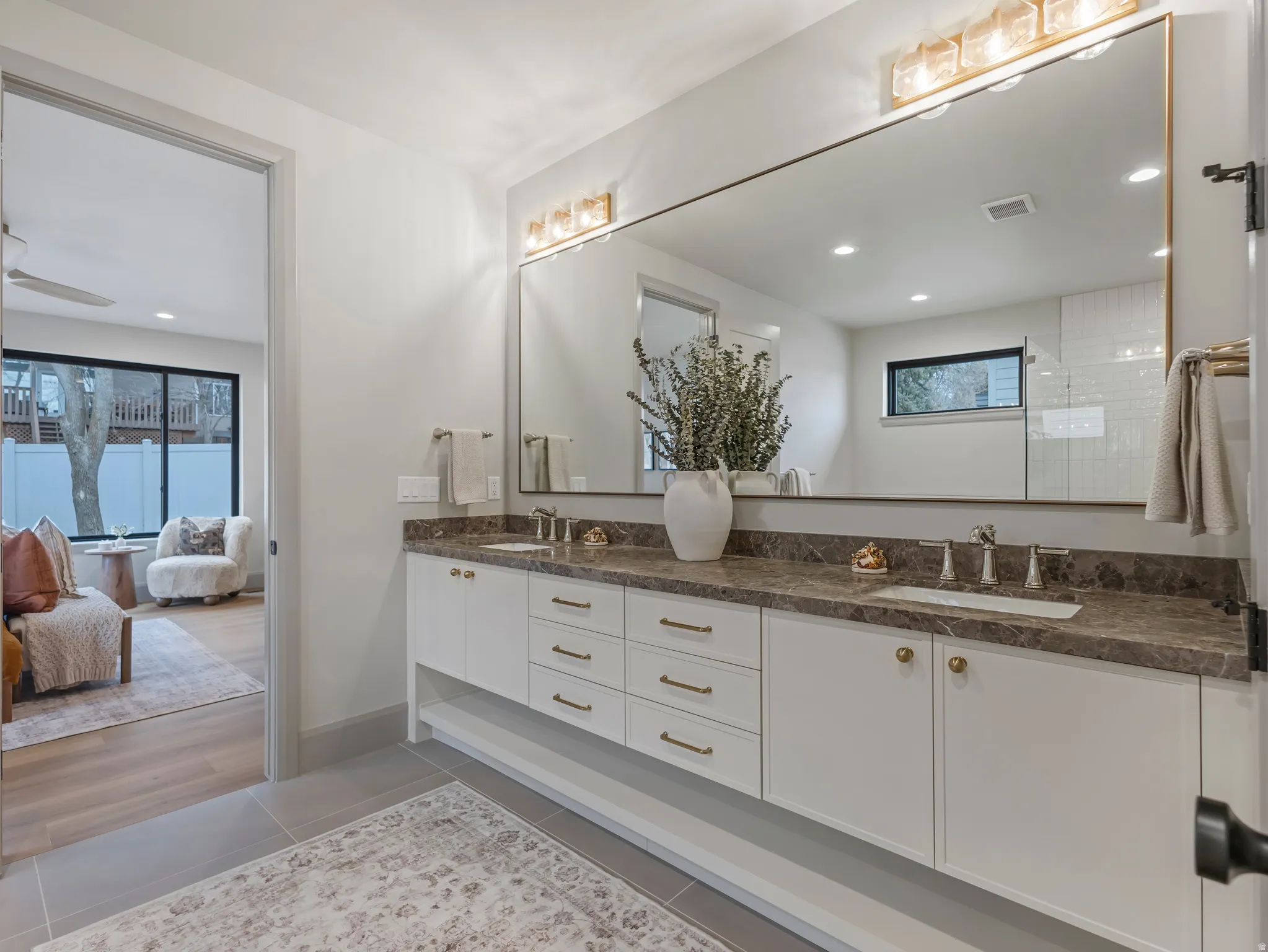 Ensuite bathroom with double vanity, light tile patterned flooring, and recessed lighting