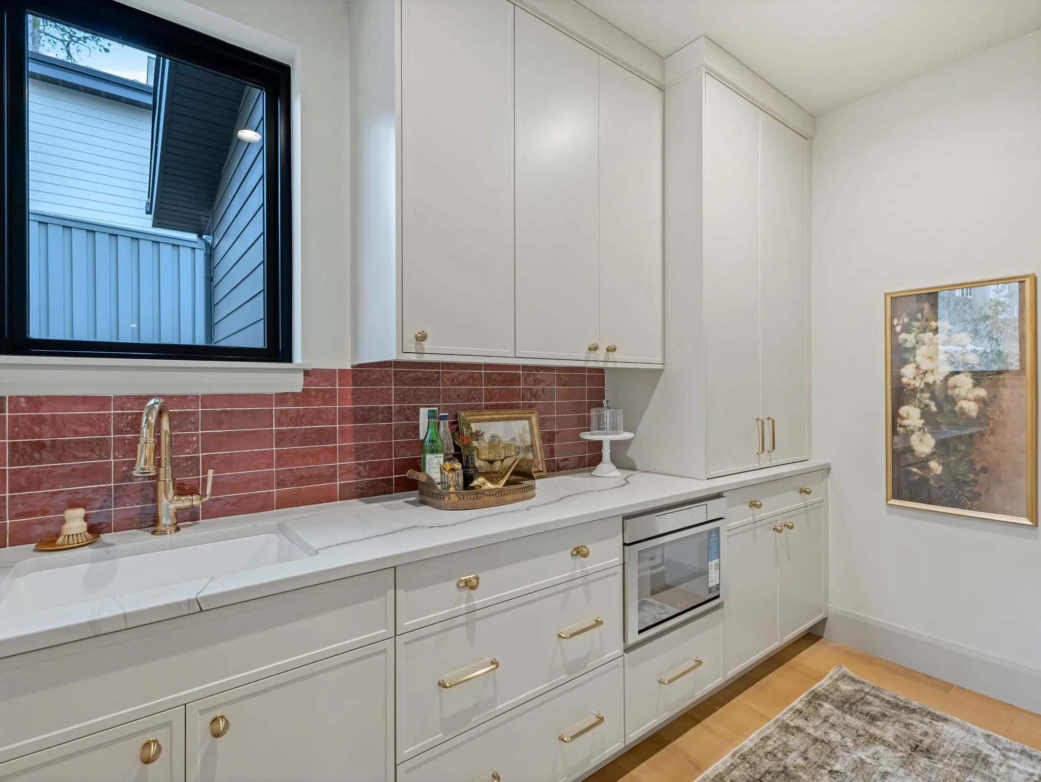 Kitchen with white cabinets, stainless steel microwave, light wood-style flooring, and light stone countertops