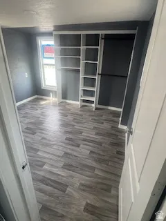 Unfurnished bedroom with dark wood-style floors and baseboards