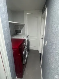 Laundry room featuring a textured wall and washing machine and clothes dryer
