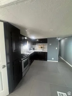 Kitchen featuring dark cabinetry, gas range, and light countertops