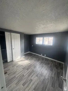 Unfurnished bedroom with a textured ceiling, wood finished floors, and a closet