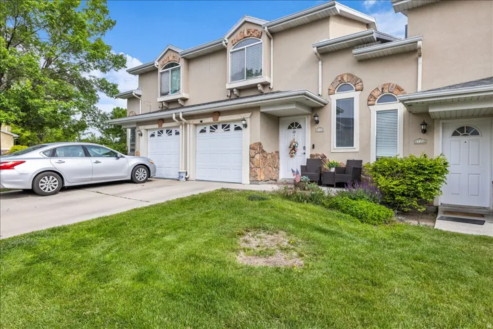 View of front of home featuring a garage, concrete driveway, stucco siding, and a front lawn