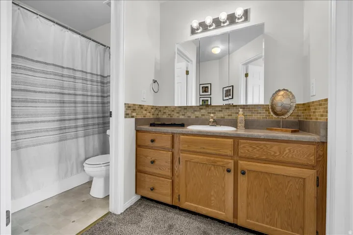 Full bathroom featuring vanity, a shower with shower curtain, light floors, and decorative backsplash
