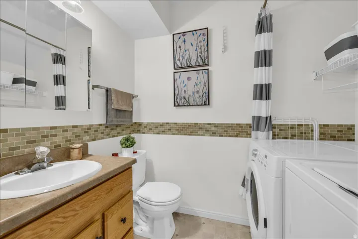 Bathroom with vanity, washer and clothes dryer, decorative backsplash, and shower / tub combo