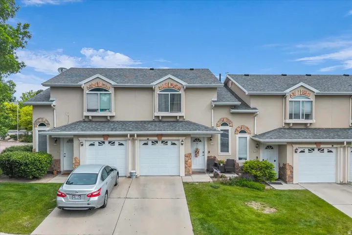 Traditional home featuring a garage, a front lawn, stucco siding, and driveway