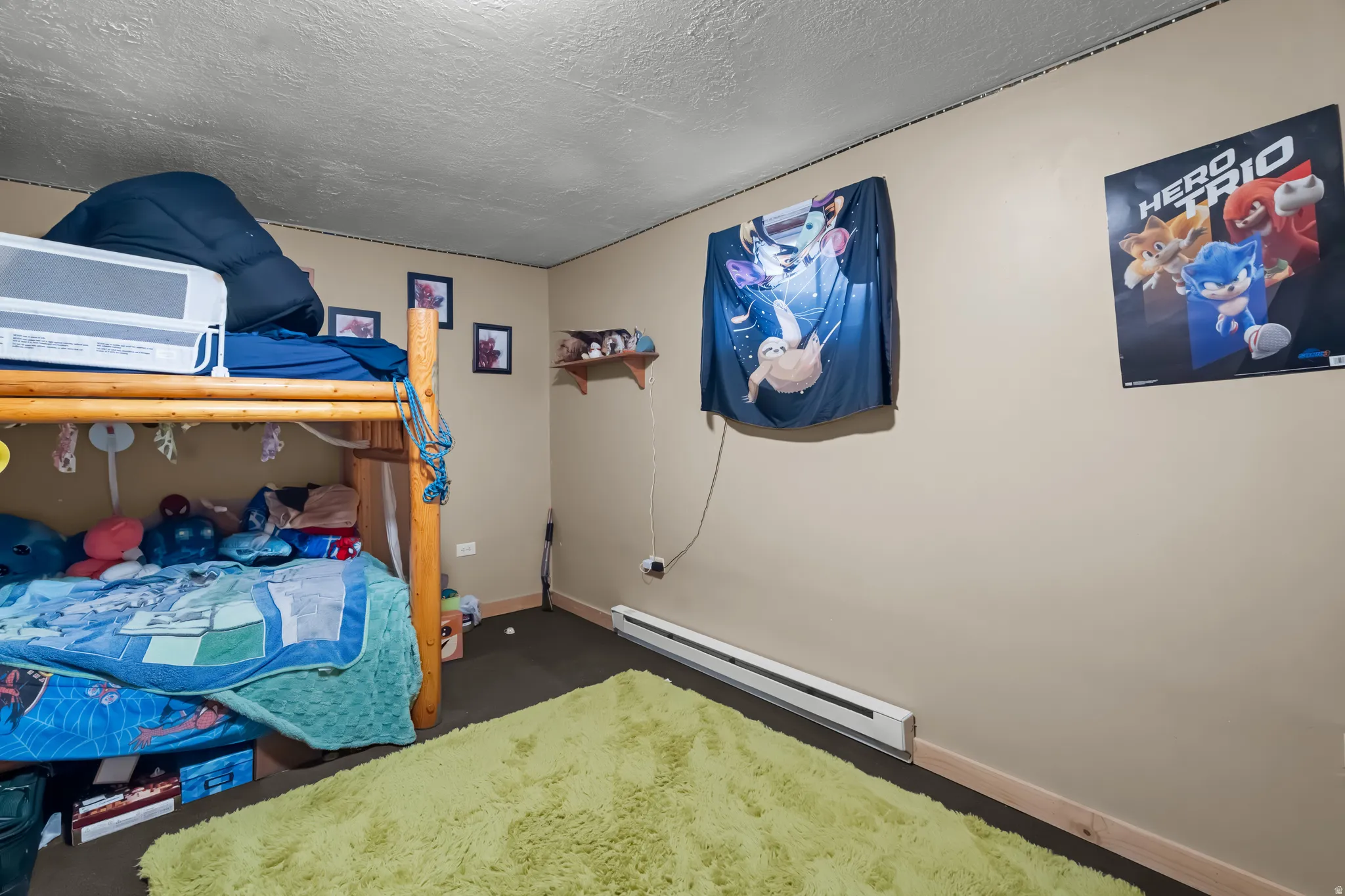 Bedroom featuring a baseboard heating unit, a textured ceiling, and dark carpet