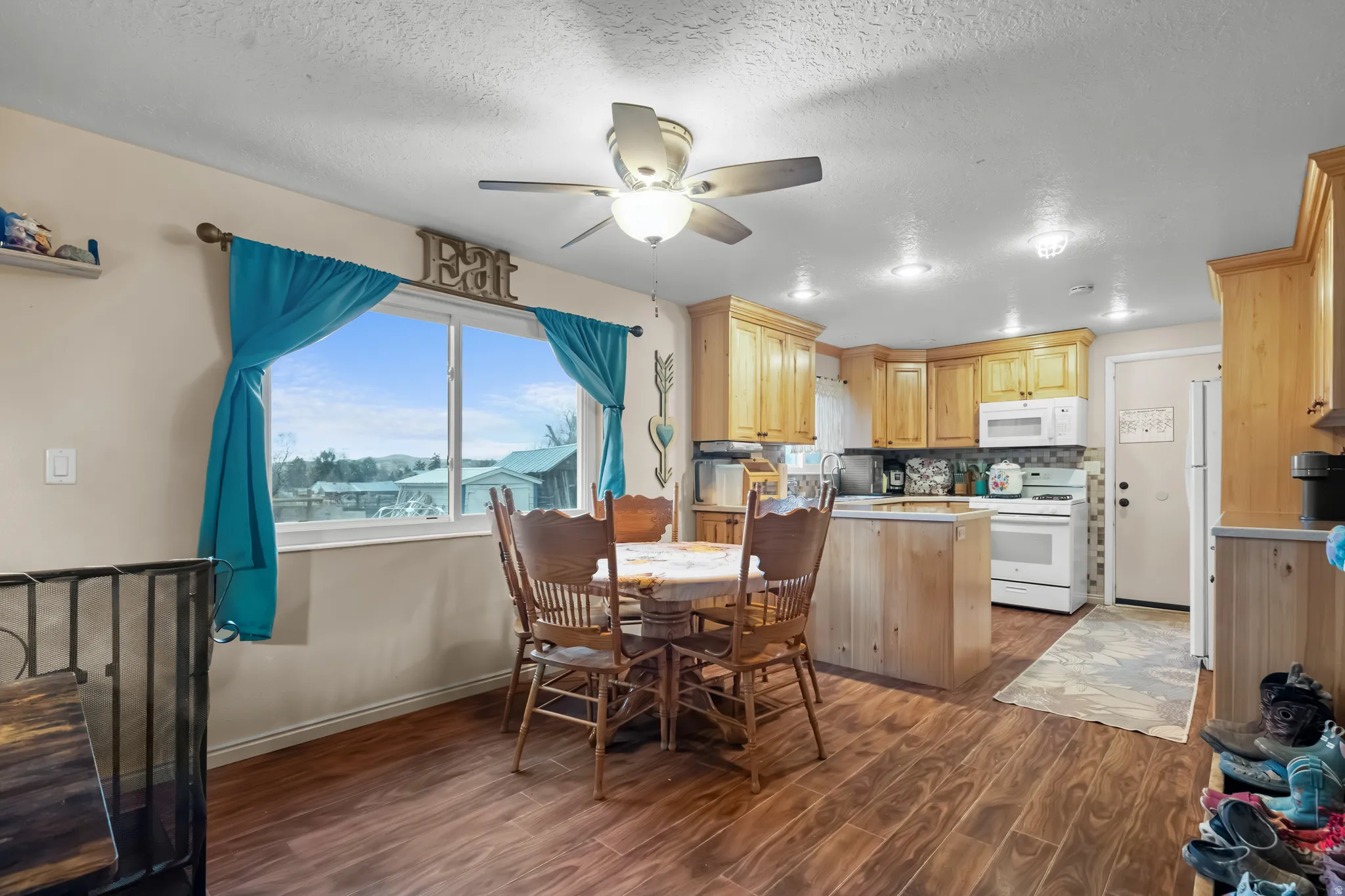 Dining room with dark wood-style flooring, a ceiling fan, and a textured ceiling