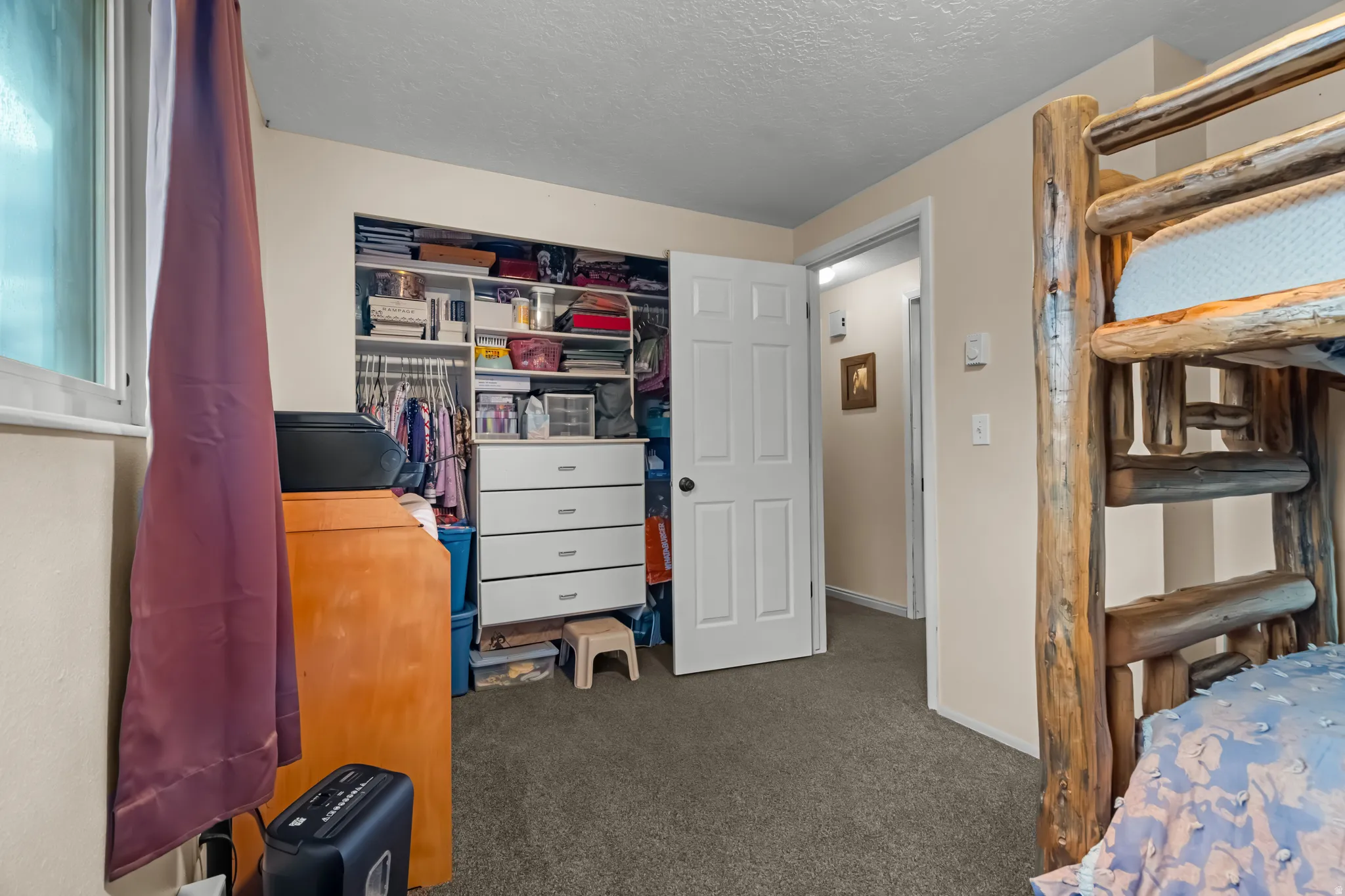 Bedroom with dark colored carpet, a textured ceiling, and a closet