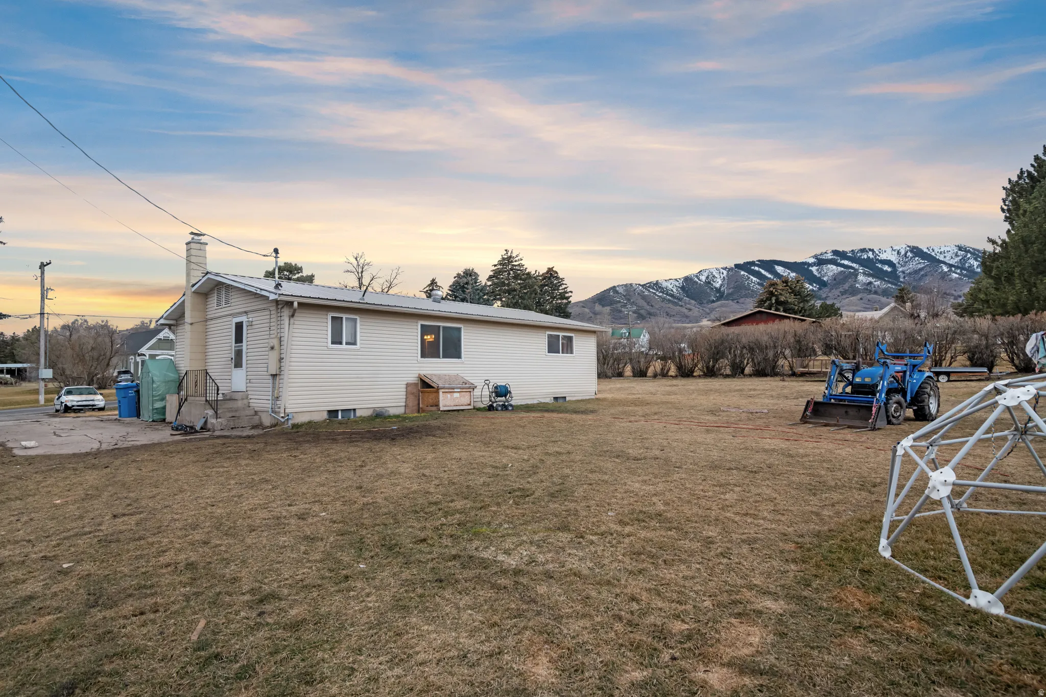 Back of property at dusk featuring a yard, a chimney, a patio, a metal roof, and entry steps