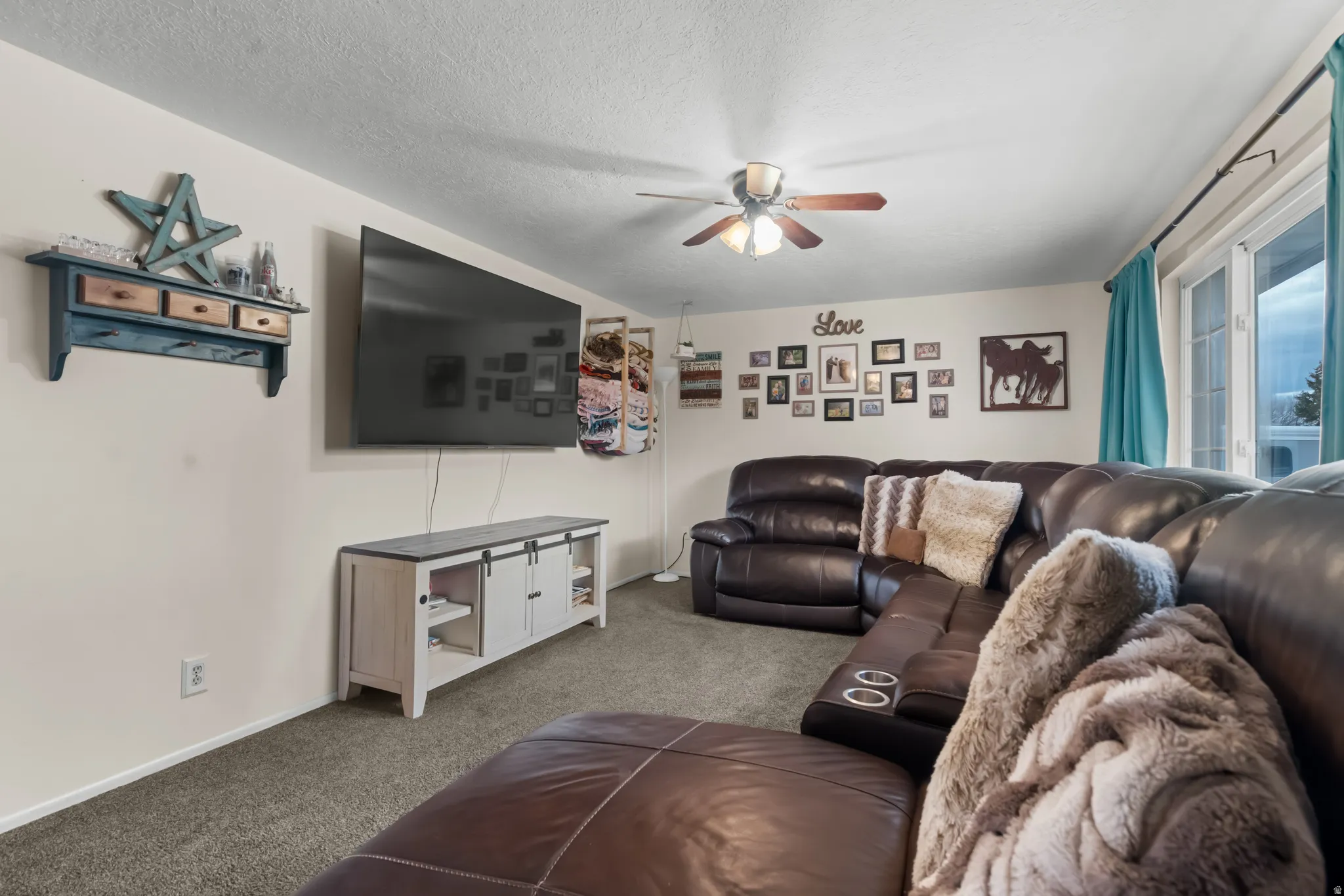 Carpeted living room featuring a ceiling fan and a textured ceiling