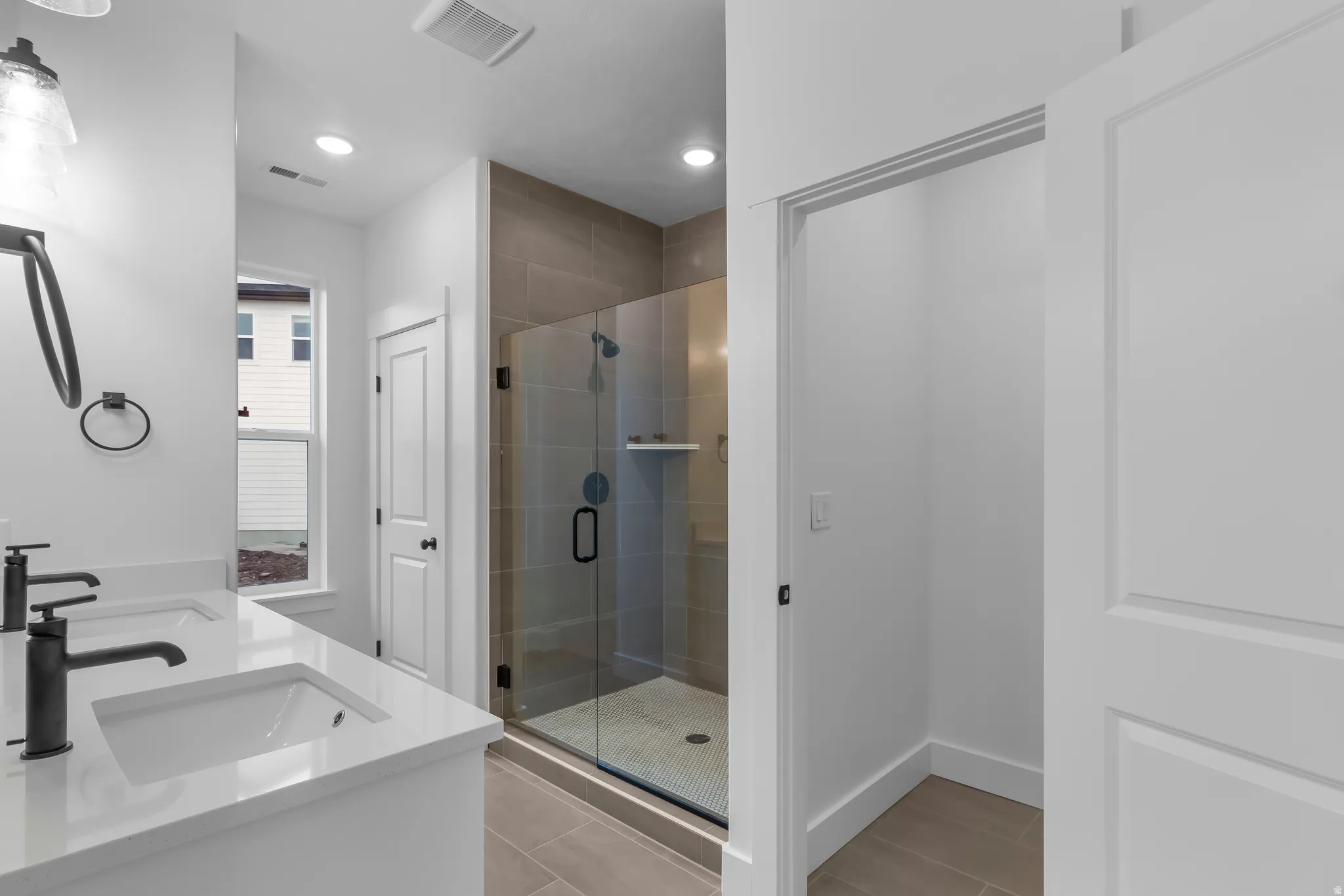 Bathroom with a stall shower, double vanity, and recessed lighting