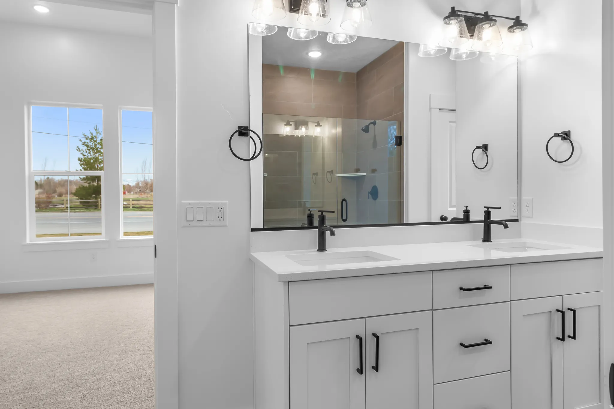 Bathroom featuring double vanity, a stall shower, and carpet floors
