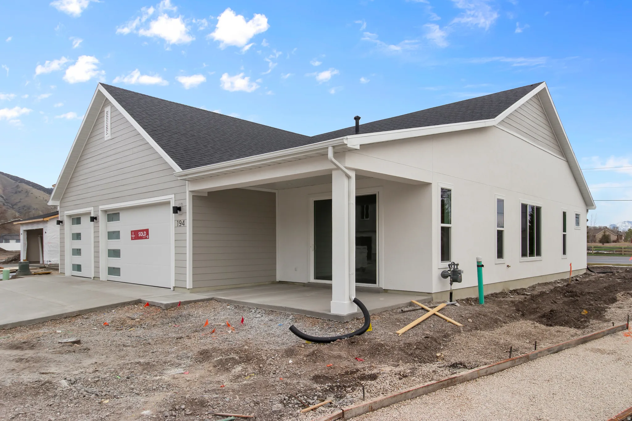 View of front facade with driveway, roof with shingles, and an attached garage