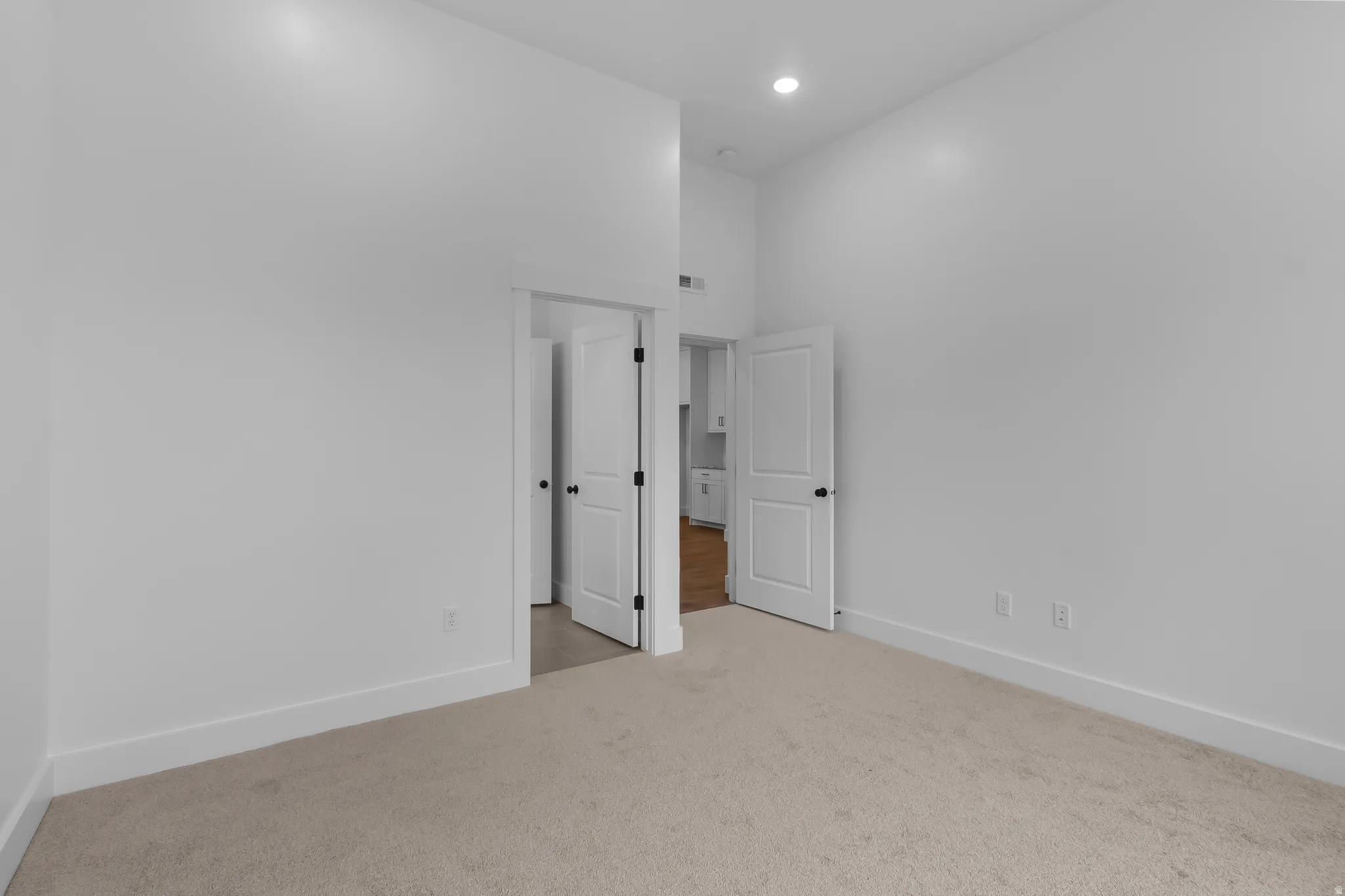 Unfurnished bedroom featuring light carpet, a high ceiling, and recessed lighting