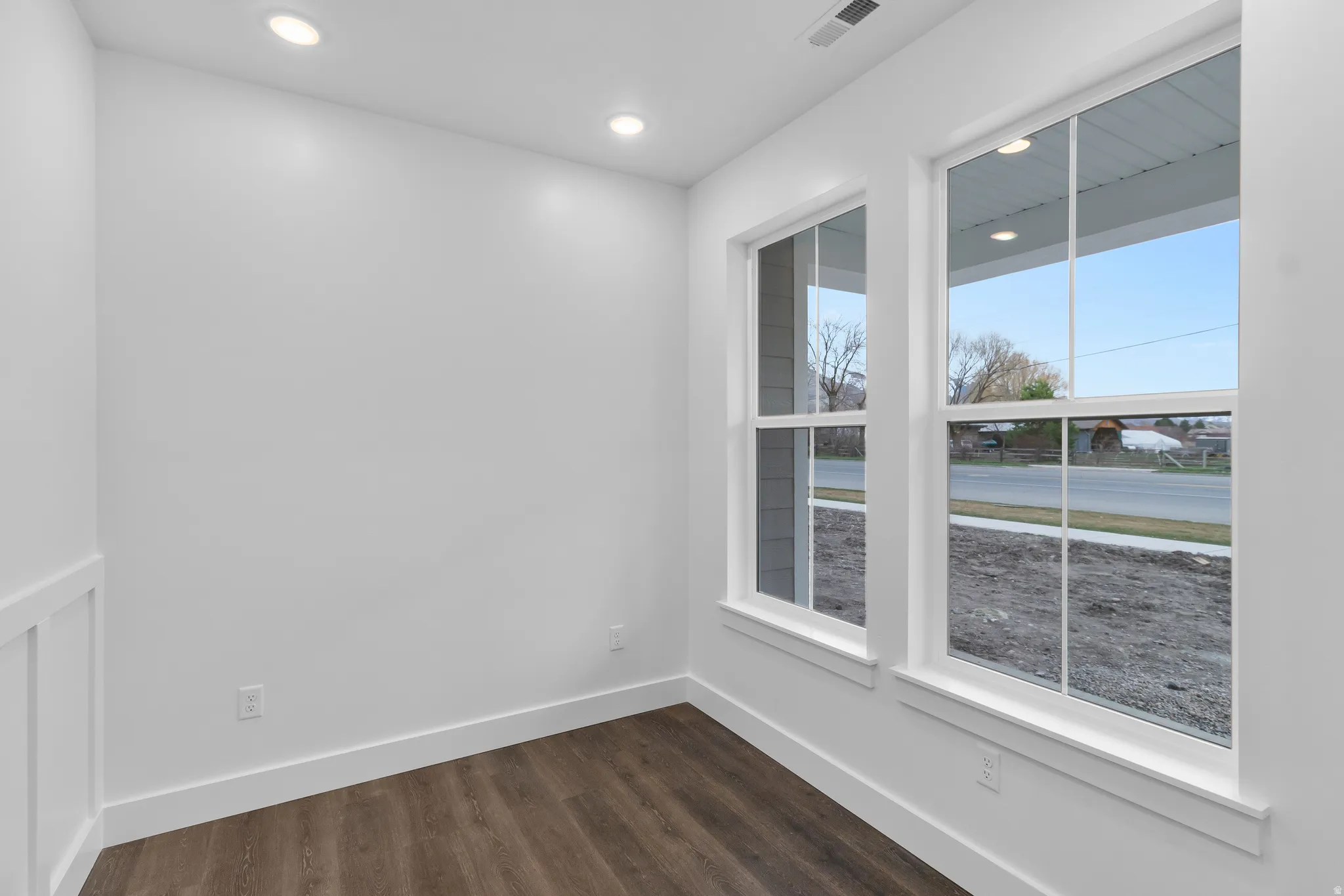 Empty room with dark wood-type flooring and recessed lighting
