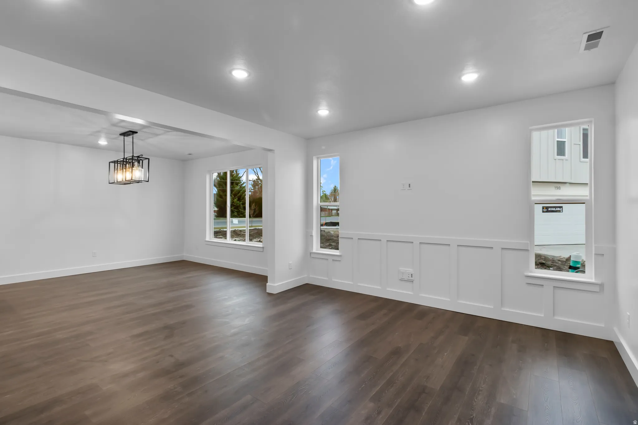 Spare room featuring a decorative wall, wainscoting, dark wood-style floors, and recessed lighting