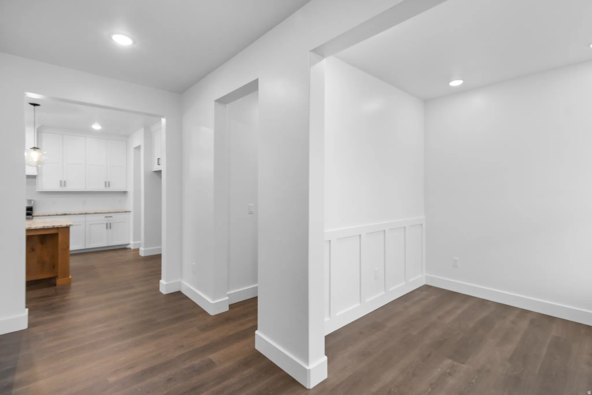 Hall with recessed lighting, dark wood-style flooring, and a wainscoted wall