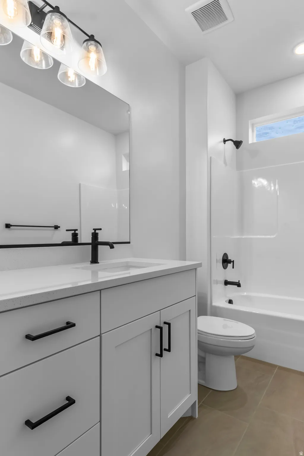 Bathroom with vanity, washtub / shower combination, and light tile patterned flooring