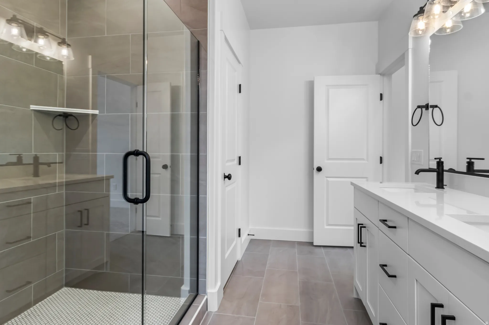 Full bath featuring double vanity, a shower stall, and light tile patterned floors