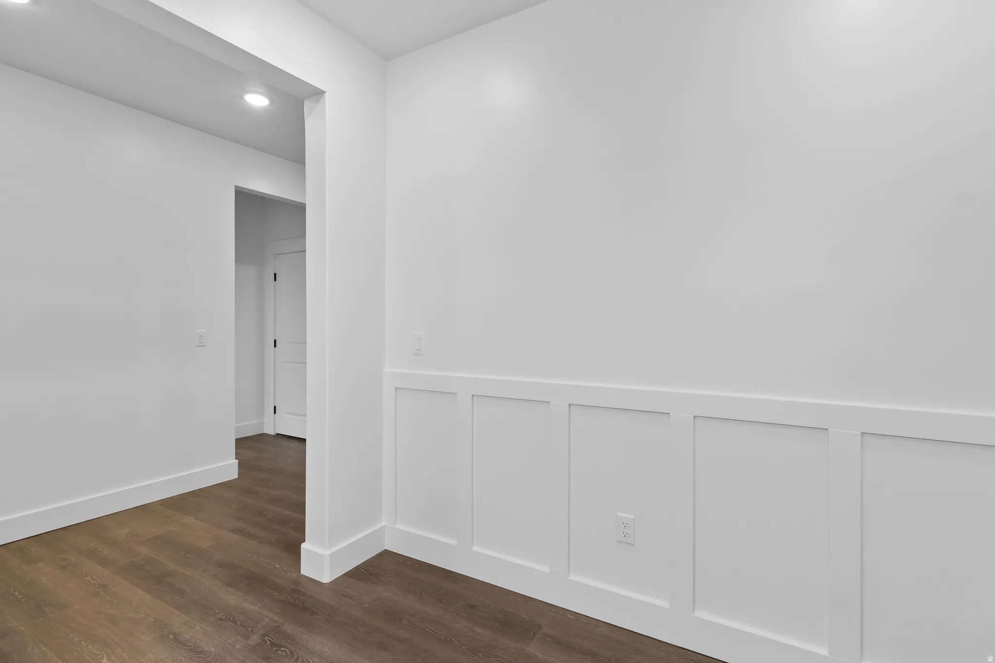 Corridor with dark wood-type flooring and recessed lighting