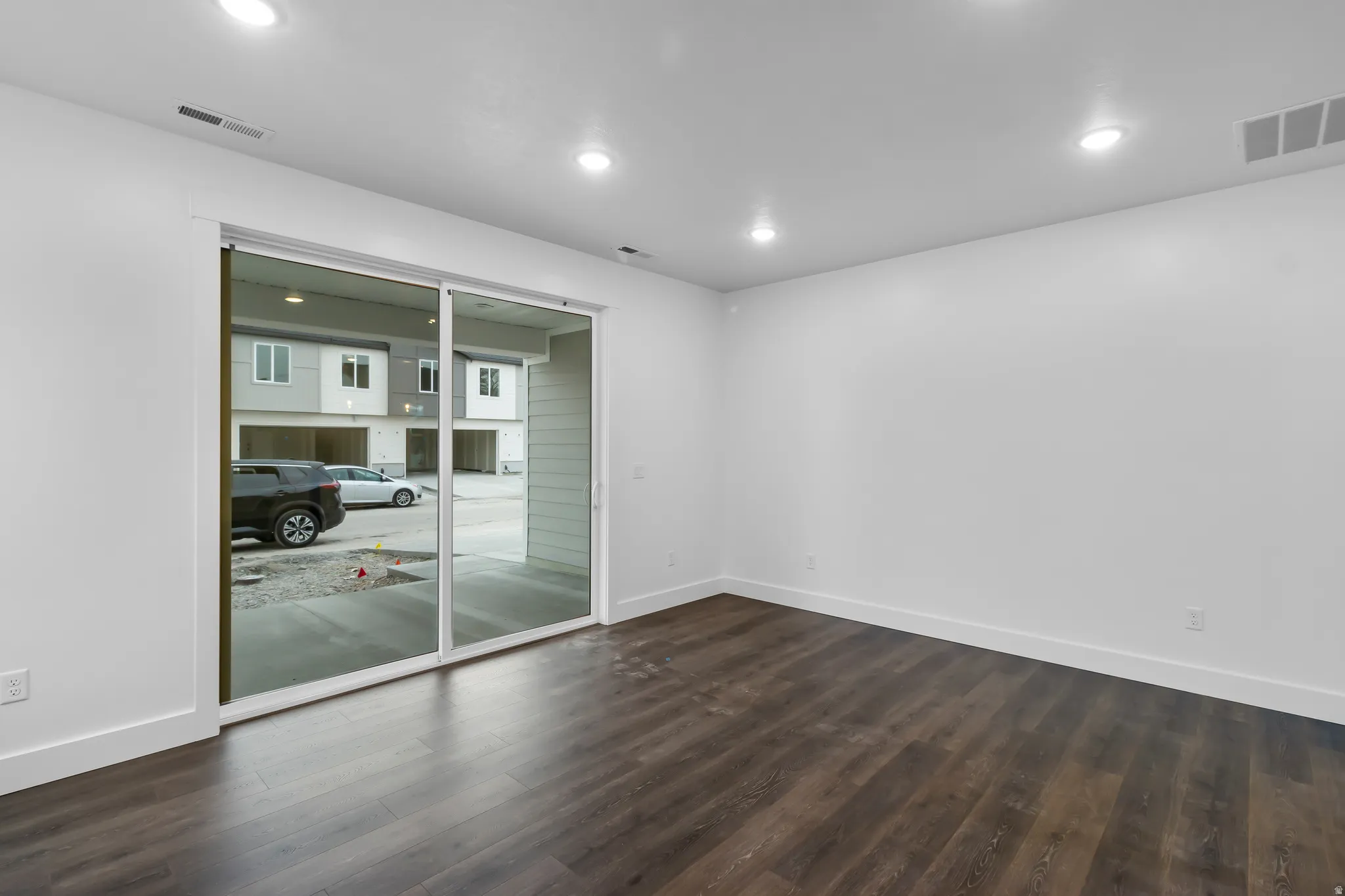 Empty room featuring dark wood-type flooring and recessed lighting