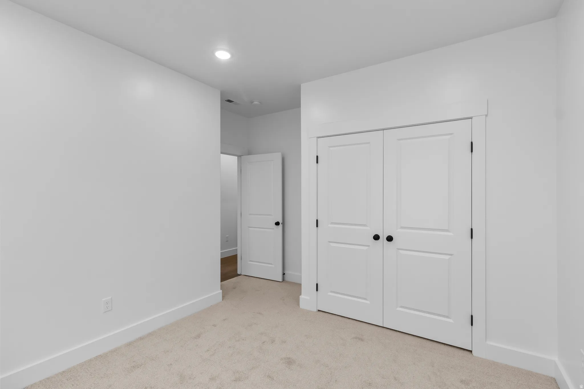 Unfurnished bedroom featuring light colored carpet, recessed lighting, and a closet