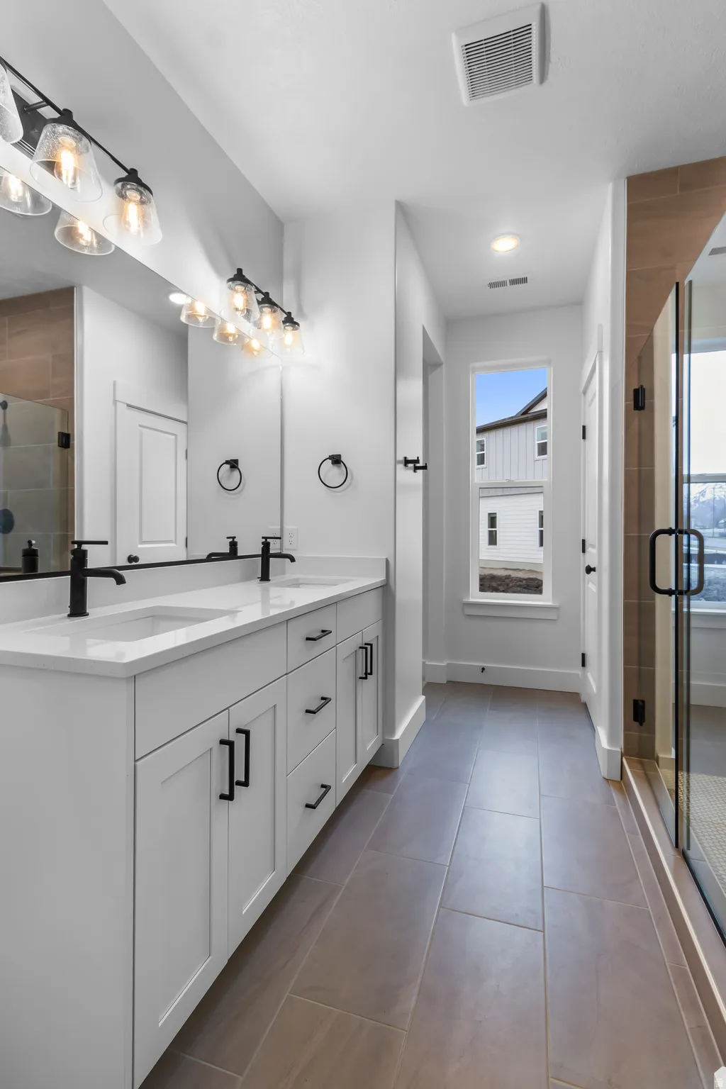 Bathroom featuring a stall shower, double vanity, and light tile patterned flooring