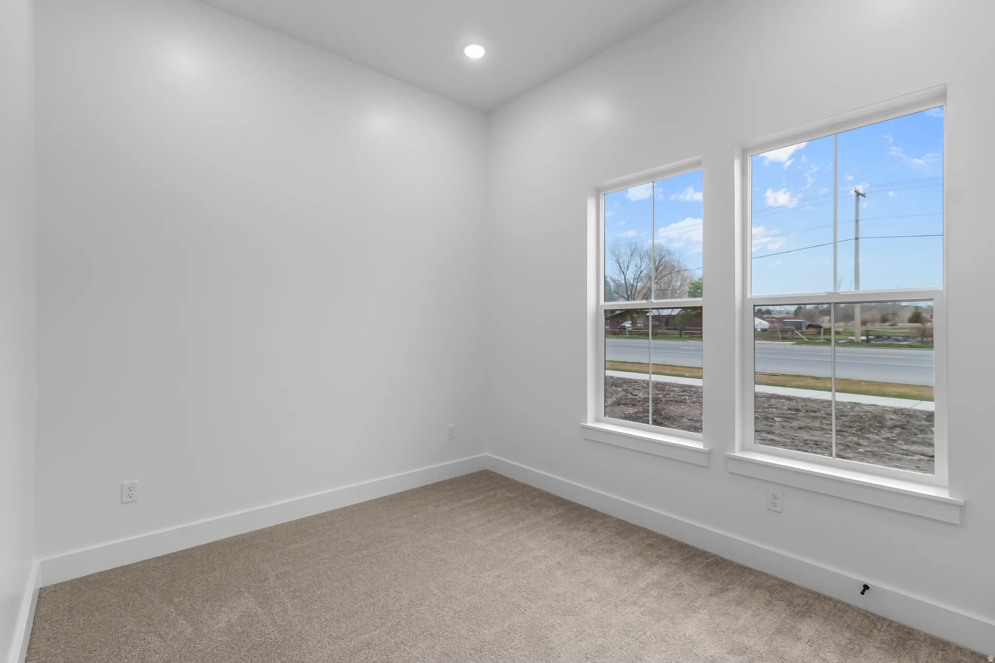 Empty room with light colored carpet and recessed lighting