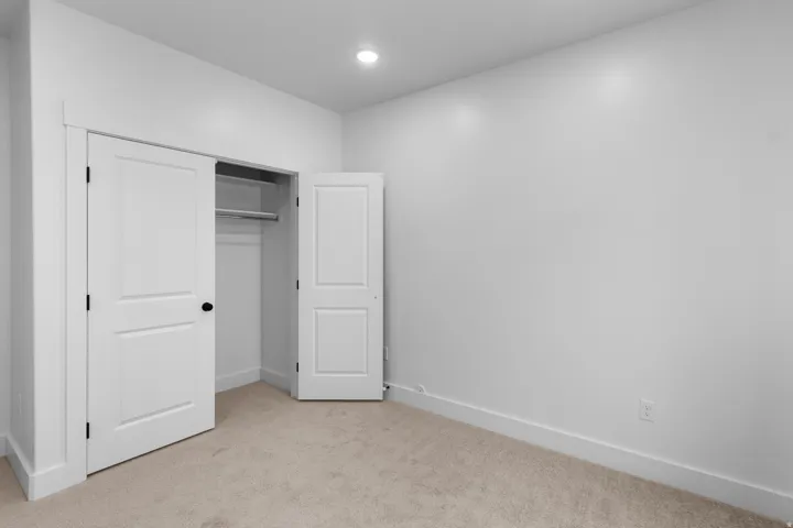 Unfurnished bedroom with light carpet, a closet, and recessed lighting
