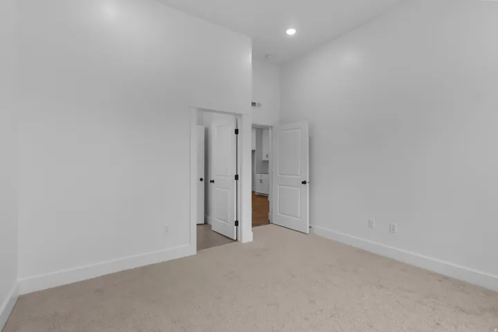 Unfurnished bedroom featuring light carpet, a high ceiling, and recessed lighting