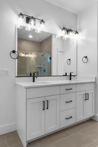 Full bathroom with double vanity, light tile patterned floors, and a shower stall
