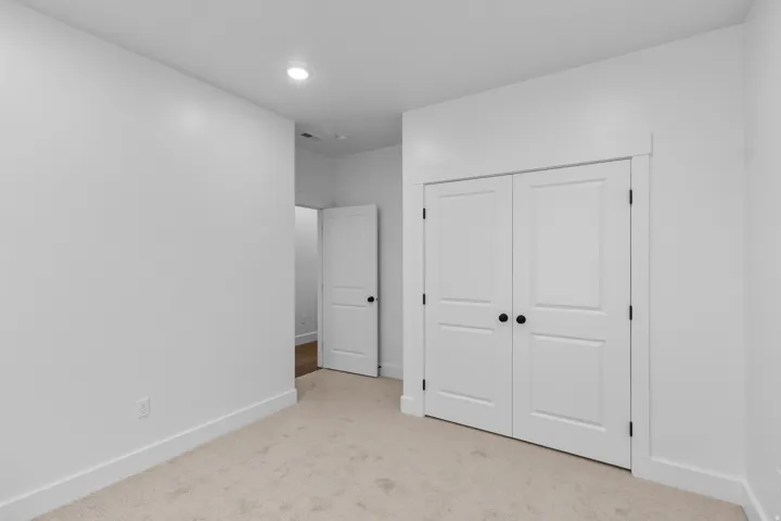 Unfurnished bedroom featuring light colored carpet, recessed lighting, and a closet